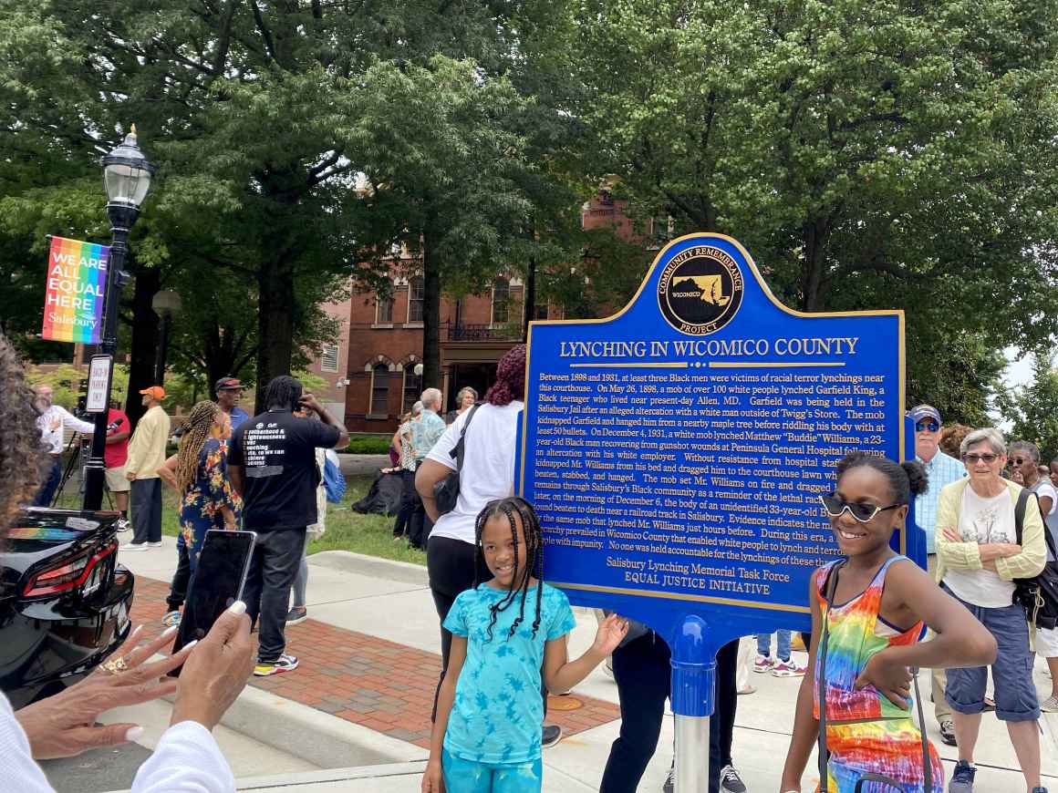 2021 Freedom Riders gather near the Lynching in Wicomico County memorial sign. A person is taking the photo of two Black children standing by the sign.