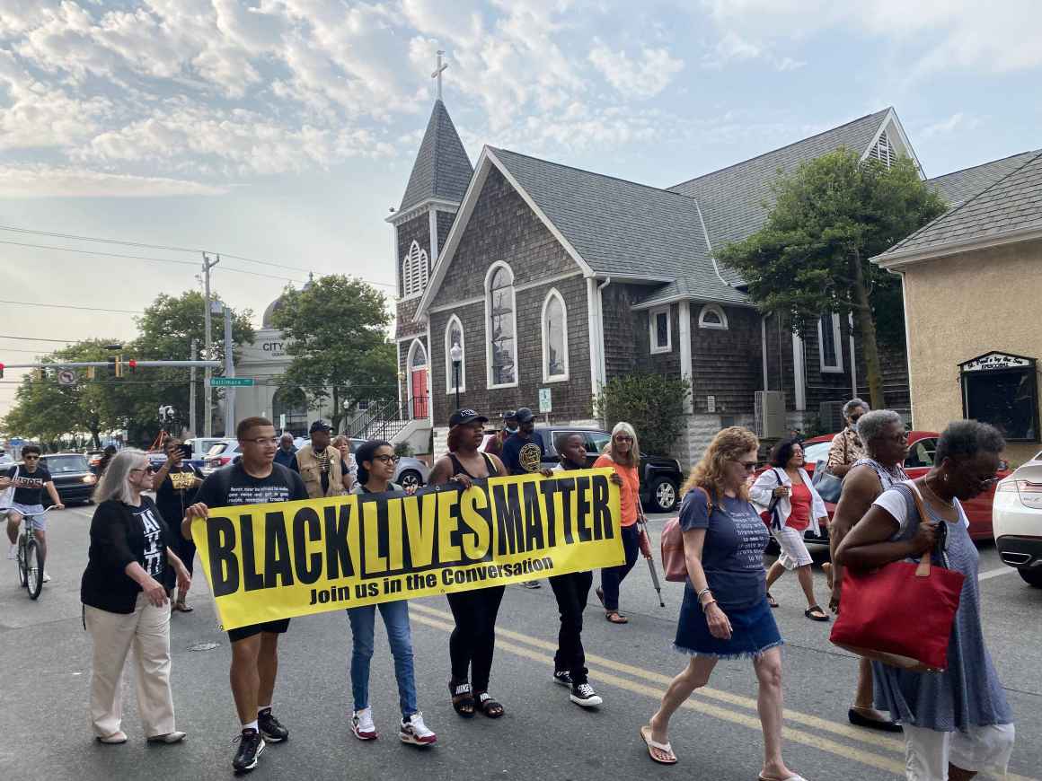 2021 Freedom Riders are marching down the street with a Black Lives Matter sign.