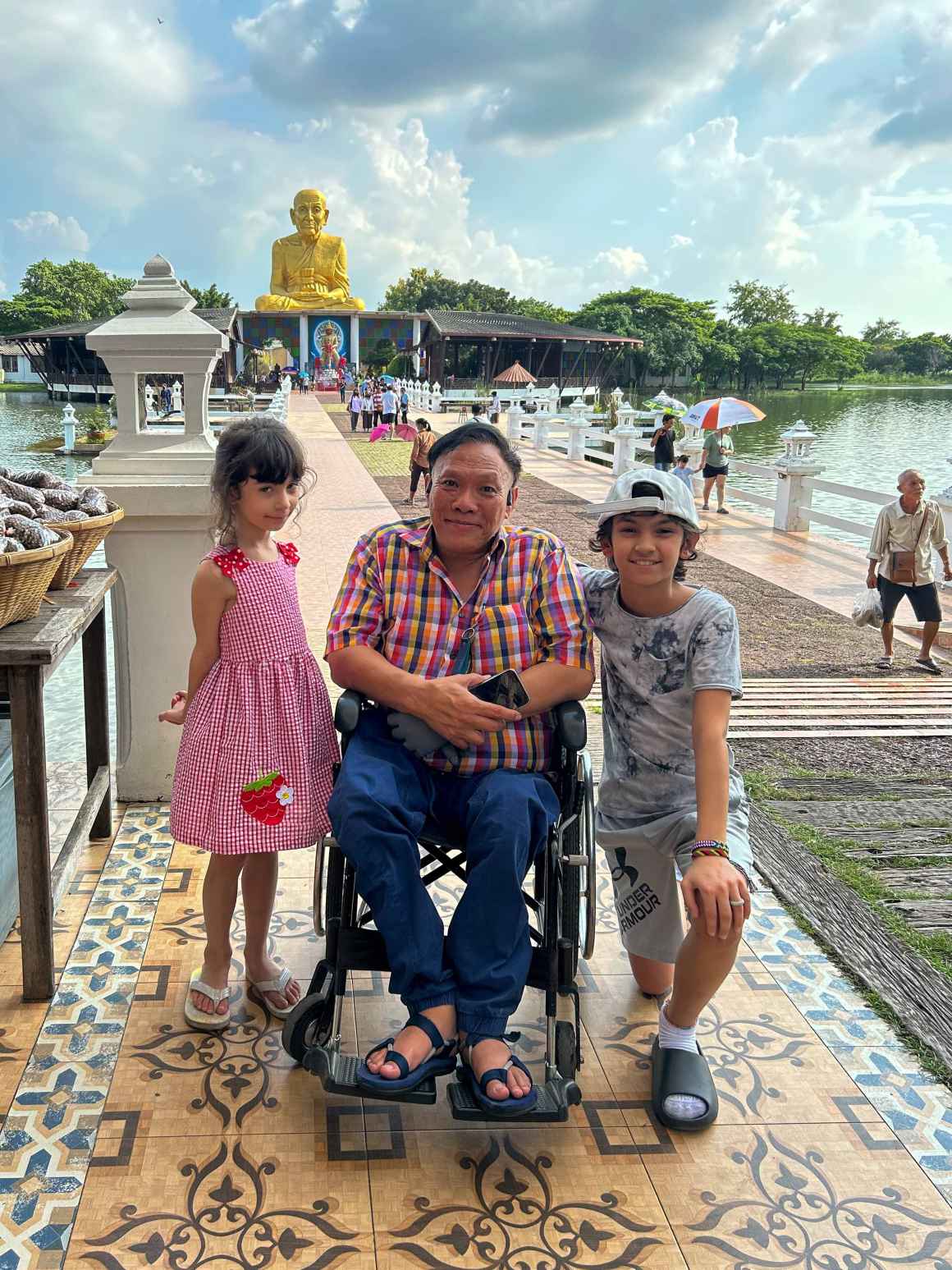 Frank's two children with a family member in a wheelchair in Thailand.